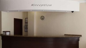 A reception area with a dark wooden counter and a sign that reads "Reception". - Alin Hotel (Alanya)