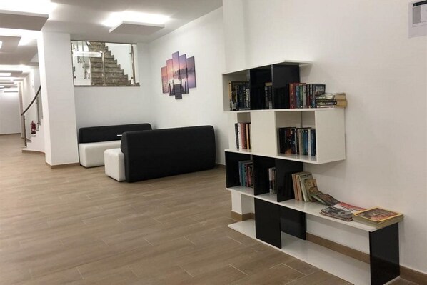 A modern living room with a black sofa, white ottoman, and a bookshelf filled with books. - Flamingo Beach Resort (Benidorm)