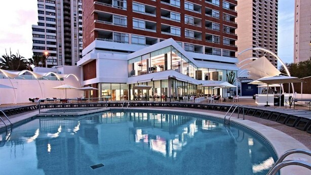 A modern hotel with a pool, outdoor seating, and a glass facade. - Flamingo Beach Resort (Benidorm)