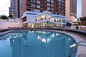 A modern hotel with a pool, outdoor seating, and a glass facade. - Flamingo Beach Resort (Benidorm)