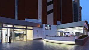 A modern hotel entrance with glass doors, a reception desk, and a landscaped area with plants. - Flamingo Beach Resort (Benidorm)