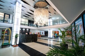 A modern lobby with a reception desk, a chandelier, and a glass railing. - Radisson Hotel Paramaribo (Paramaribo)