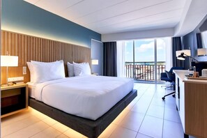 A hotel room with a large bed, a desk, a chair, and a balcony with a view. - Radisson Hotel Paramaribo (Paramaribo)