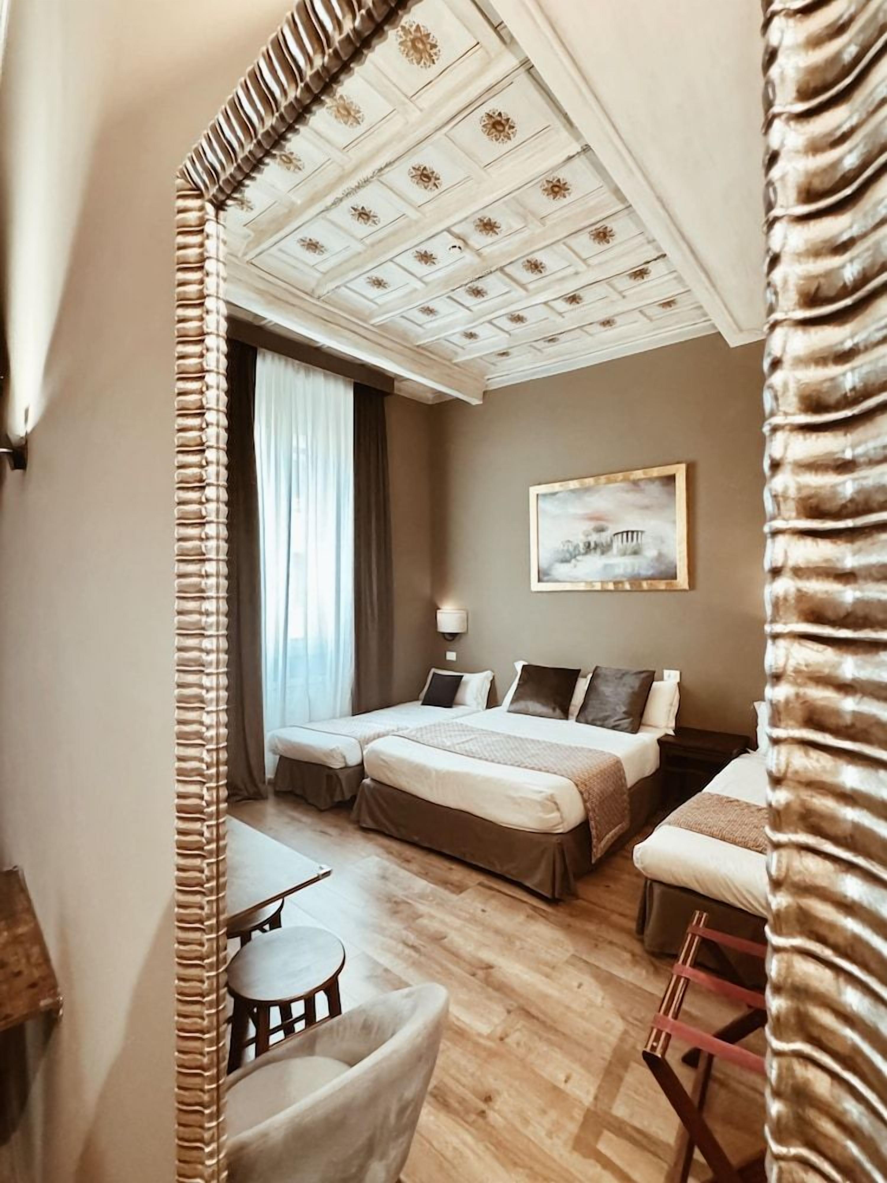 A hotel room with a large mirror, two beds, a desk, and a chair.