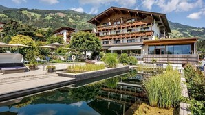 A hotel with a pool, outdoor seating, and mountain views. - Crystal Hotel (Fuegen)