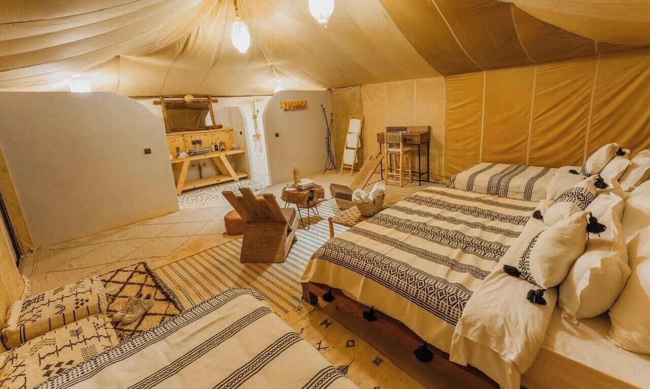 Uma tenda com cama, cadeiras e uma pequena mesa.