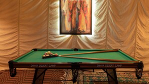 Una mesa de billar con una obra de arte enmarcada encima, con la etiqueta 'Dihya Desert Camp'.