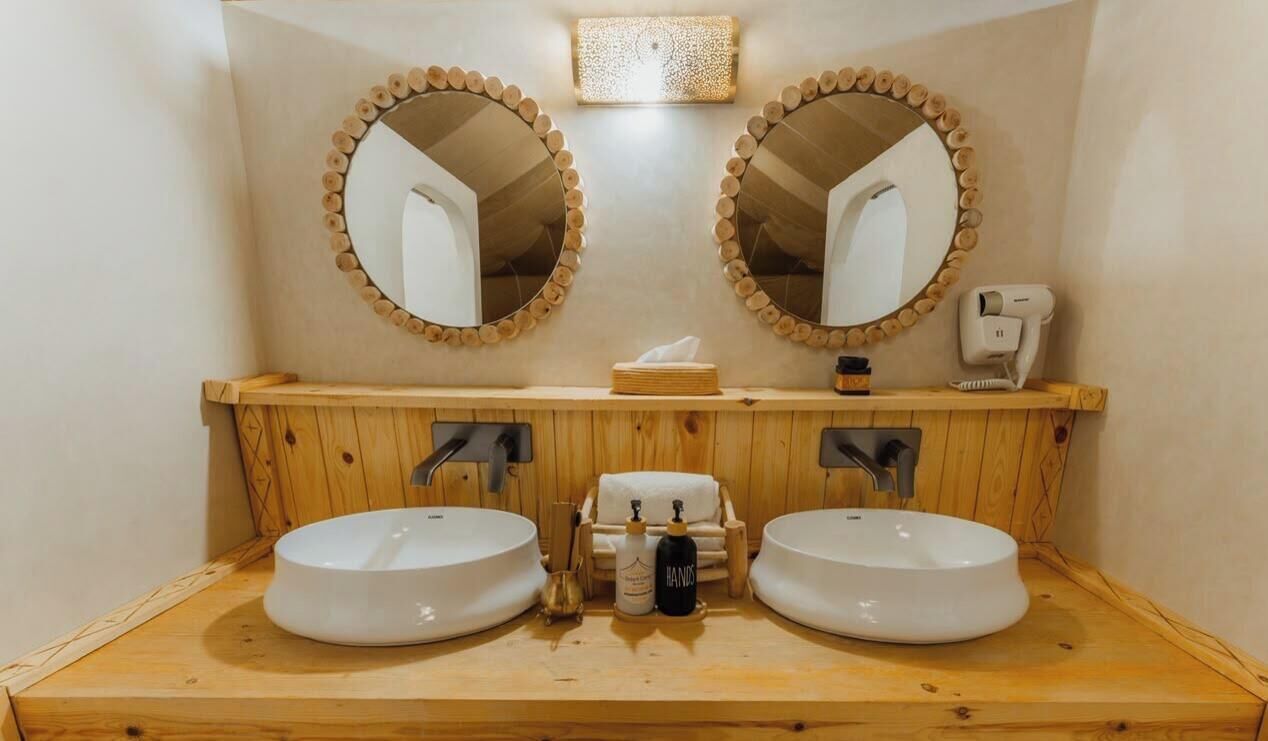 A bathroom with two sinks, wooden vanity, and a towel dispenser.