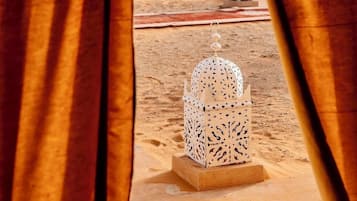A desert scene with a white tent and a decorative lantern in the foreground.