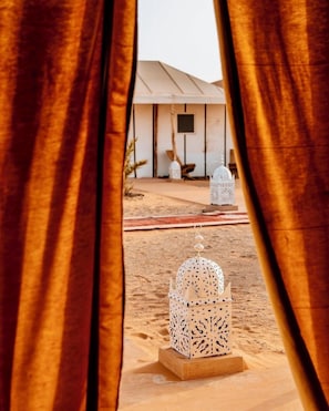 A desert scene with a white tent and a decorative lantern in the foreground. - Dihya Desert Camp (Taouz)