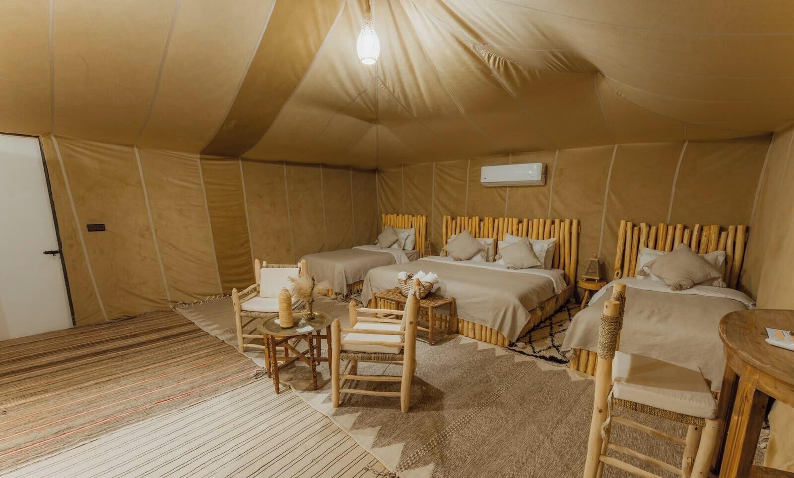 Una habitación con carpa, dos camas, una mesa y una silla.