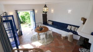 Une pièce chaleureuse avec une table ronde, des chaises blanches, un canapé bleu et une cheminée.