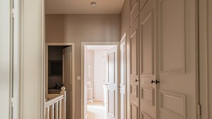A hallway with wooden flooring, white walls, and a series of white doors on one side. - Charming house in Burgundy (Saint-Gengoux-le-national)