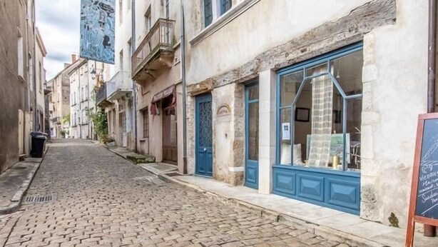A cobblestone street lined with historic buildings, some with blue shutters and balconies. - Charming house in Burgundy (Saint-Gengoux-le-national)