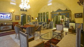 A hotel lobby with a chandelier, seating area, and a television displaying a news channel. - Carthage Hill (Carthage)