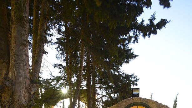 A rustic stone building with a cozy interior, a dining table with chairs, and a small garden area. - Carthage Hill (Carthage)