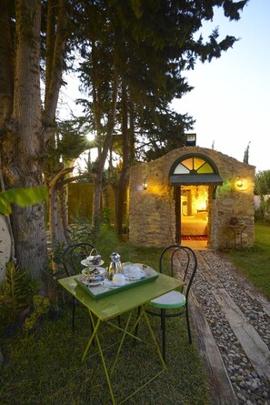 Un edificio rústico de piedra con un interior acogedor, una mesa de comedor con sillas y un pequeño jardín.