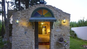 A stone-built structure with a doorway leading to a room with a bed and a table. - Carthage Hill (Carthage)