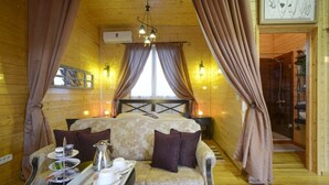 A cozy wooden cabin room with a sofa, a tray with tea and snacks, and a bed with curtains. - Carthage Hill (Carthage)