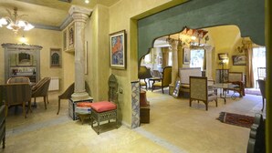 A spacious room with a high ceiling, a large window, and a chandelier. There are several chairs and a table with a vase. - Carthage Hill (Carthage)