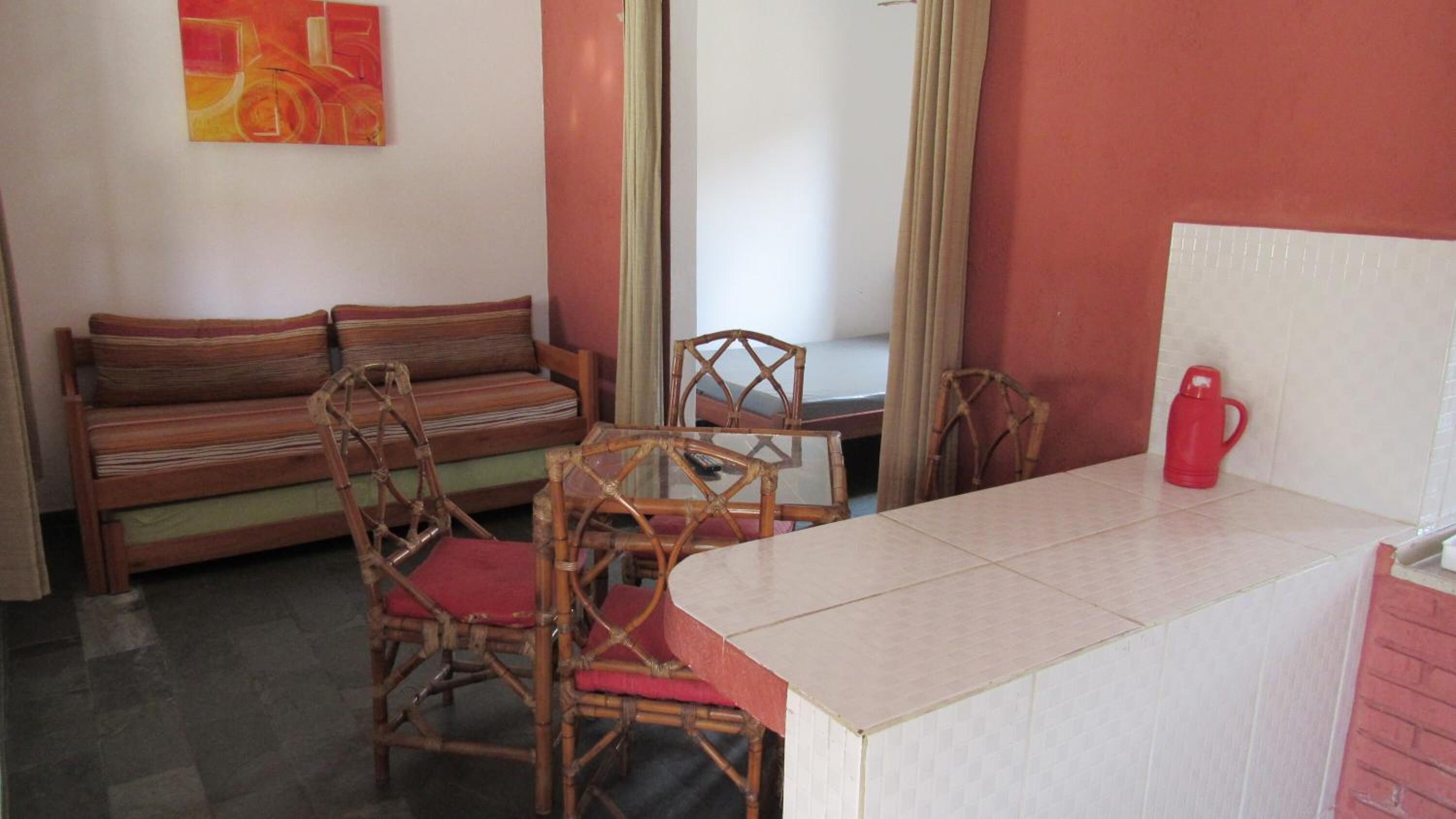 Une pièce avec un canapé, deux fauteuils, une table et une bouilloire rouge.