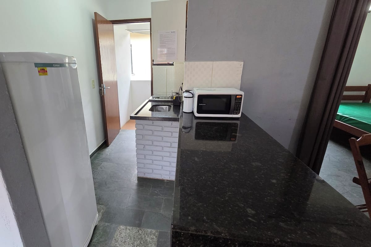 Una cocina estrecha con un refrigerador, un microondas y un lavamanos.