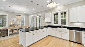 A modern kitchen with white cabinetry, a black countertop, and stainless steel appliances. - Pet-Friendly WaterColor Retreat | Pool Spring '27 | Cart & Bikes (Santa Rosa Beach, Florida)