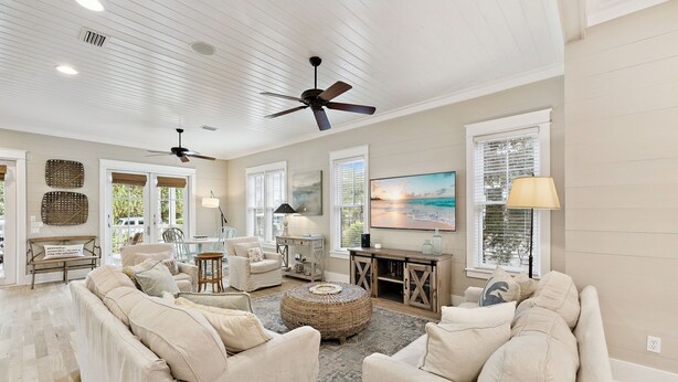A spacious living room with a high ceiling, ceiling fans, and large windows. There are multiple seating areas with sofas and a coffee table. - Pet-Friendly WaterColor Retreat | Pool Spring '27 | Cart & Bikes (Santa Rosa Beach, Florida)