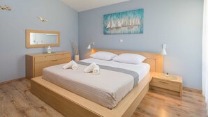 A bedroom with a bed, nightstands, a dresser, a mirror, and a painting.
