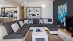 A modern living room with a sectional sofa, a coffee table, a TV, and a painting on the wall.