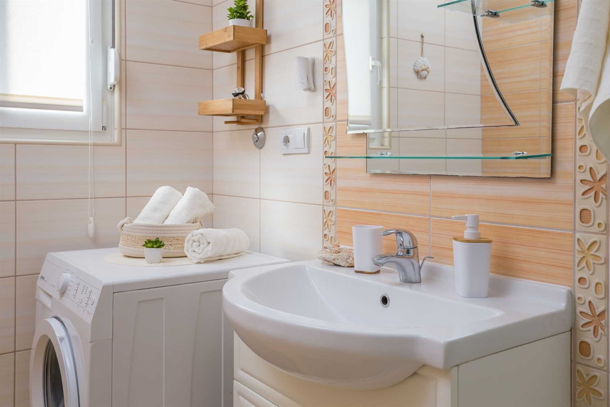 A bathroom with a white sink, a mirror, a glass shelf, and a washing machine.