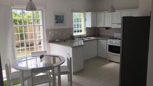 A kitchen with white cabinets, a gas stove, a sink, and a dining area with a table and chairs.