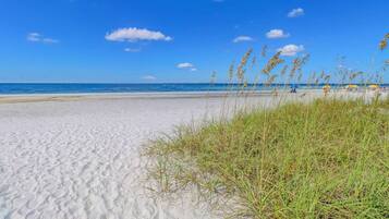Ein Sandstrand mit blauem Himmel und weiter Meereslinie.