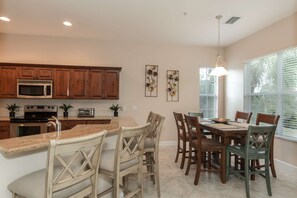 A modern kitchen with wooden cabinets, stainless steel appliances, and a dining area with a large table and chairs.