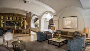 Een ruime lobby met een bar, zitgedeeltes en een groot kunstwerk in een lijst aan de muur.