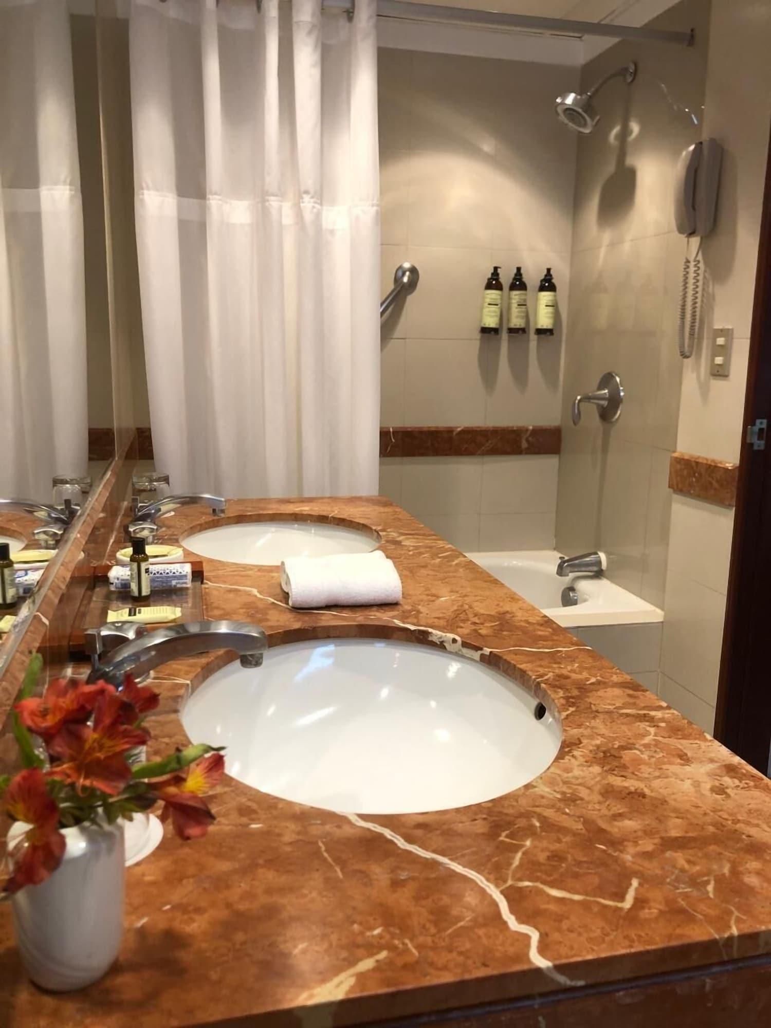 Un baño con dos lavamanos, una ducha y un espejo.