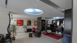 A modern hotel lobby with a reception desk, seating area, and artwork on the walls. - Razvan (Bucharest)