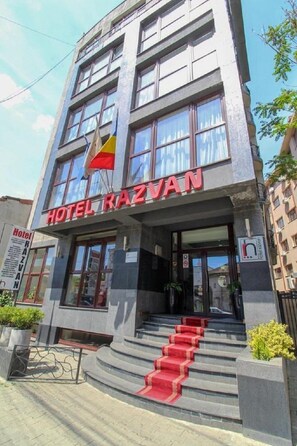 A hotel named "Hotel Razvan" with a modern facade, large windows, and a red carpeted entrance. - Razvan (Bucharest)