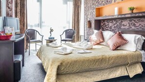 A hotel room with a bed, two chairs, a desk with a computer, and a TV. - Razvan (Bucharest)