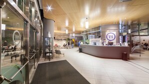 A modern hotel lobby with a reception desk, seating area, and glass partitions.