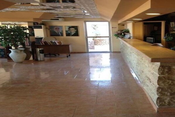 A reception area with a stone counter, a potted plant, and a large window.