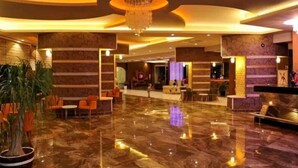 A spacious lobby with a marble floor, a reception desk, and seating areas. - Asrin Beach (Alanya)