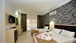 A hotel room with two beds, a desk, a television, and an air conditioning unit. - Asrin Beach (Alanya)