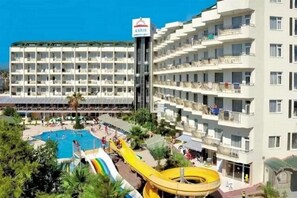 A hotel with multiple floors, a swimming pool, and a water slide. - Asrin Beach (Alanya)