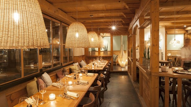 A restaurant with wooden interiors, large windows, and hanging wicker lamps. - Hotel Chartreuse (Hilterfingen)