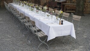 A long dining table set with white tablecloths, chairs, and floral centerpieces. - Hotel Chartreuse (Hilterfingen)