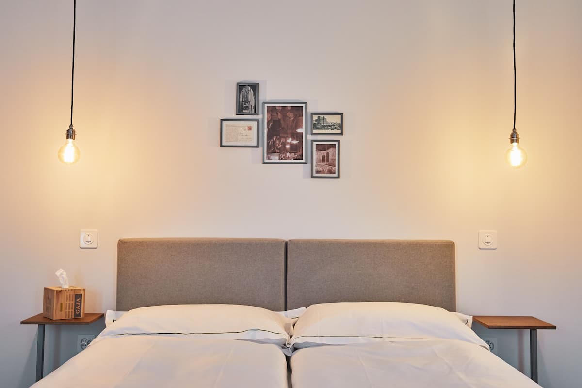 A neatly made bed with a headboard, two bedside tables, and framed pictures on the wall.