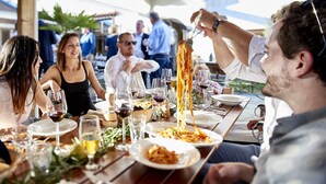 A dining table with plates of food, glasses of wine, and a person serving spaghetti. - Hotel Chartreuse (Hilterfingen)