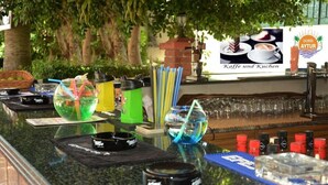 A bar area with various drink dispensers, glasses, and a sign advertising coffee and cakes. - Doris Aytur (Alanya)
