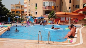 A swimming pool area with multiple water slides, lounge chairs, and umbrellas. - Doris Aytur (Alanya)